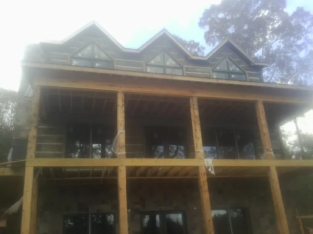 Dormers and porch framing on a large log home under construction — Roof Coating work by our crew in Glen Wild