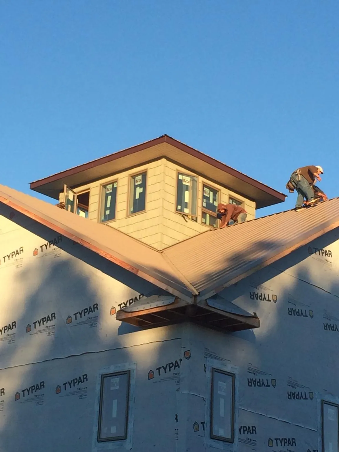 Roofers working around a rooftop cupola on a new metal roof at sunset — Roof Waterproofing in Glen Wild by Roofing Brothers